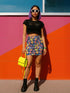 High-waisted bodycon mini skirt with an allover print of rainbow monarch butterflies and colorful tropical flowers on a dark background. Soft, stretchy poly-spandex fabric hugs the body for a flattering fit. Styled for rave, Y2K, and festival outfits. Sizes XS to XL.